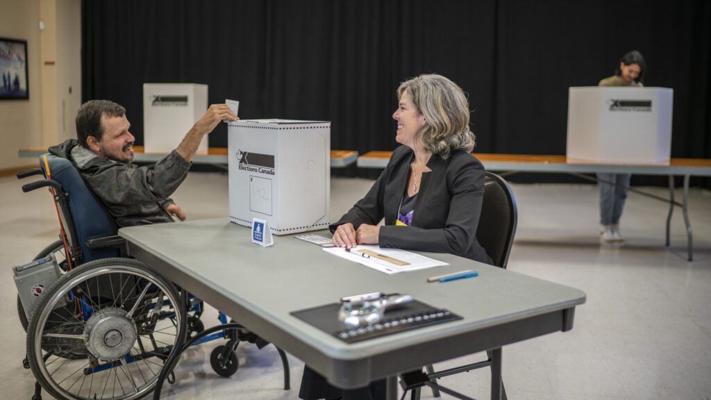 An elector in a wheelchair casting a ballot at a polling station